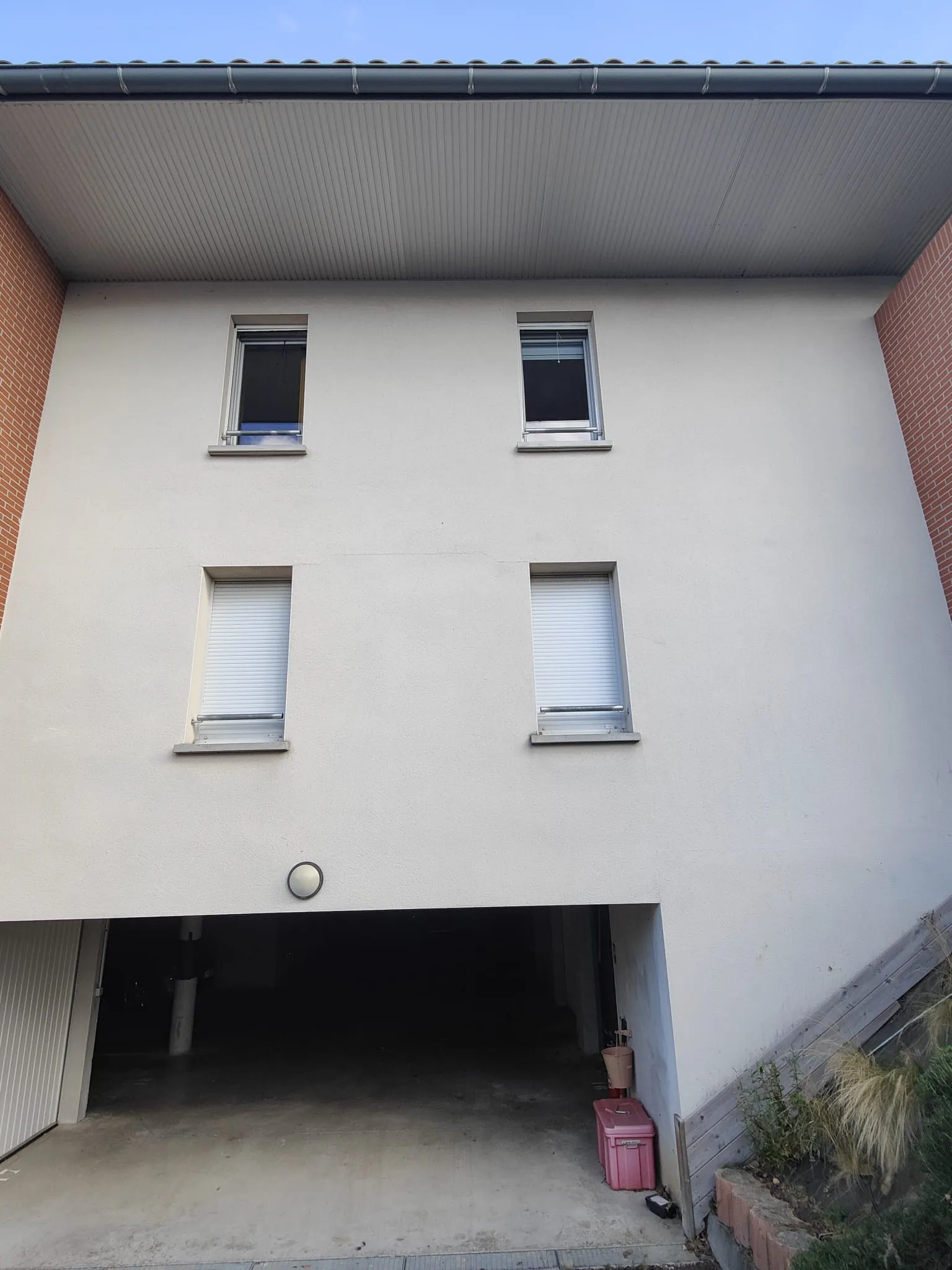 Façade d'immeuble en enduit clair vue de face, sous-face du débord de toit complète