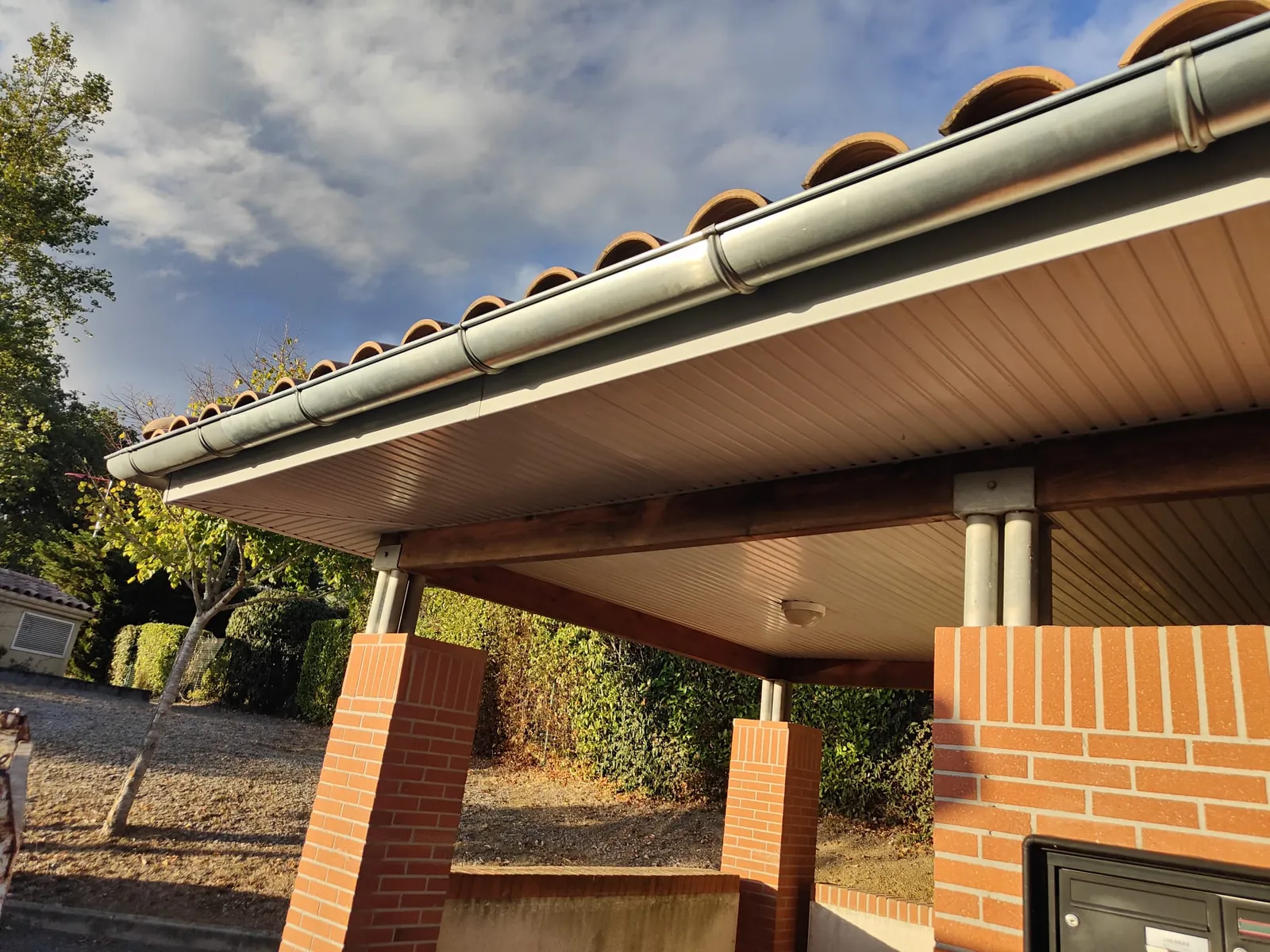 Débord de toit du local technique avec lambris PVC complet et gouttière en zinc