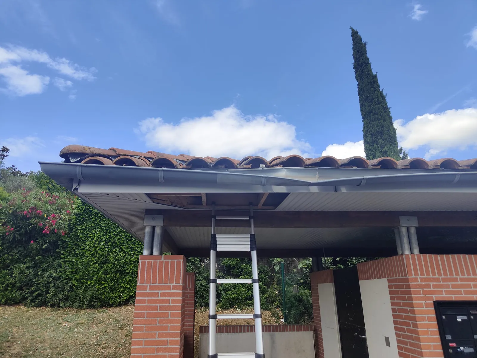 Local technique en brique couvert de tuiles, lambris arraché sous le débord de toit