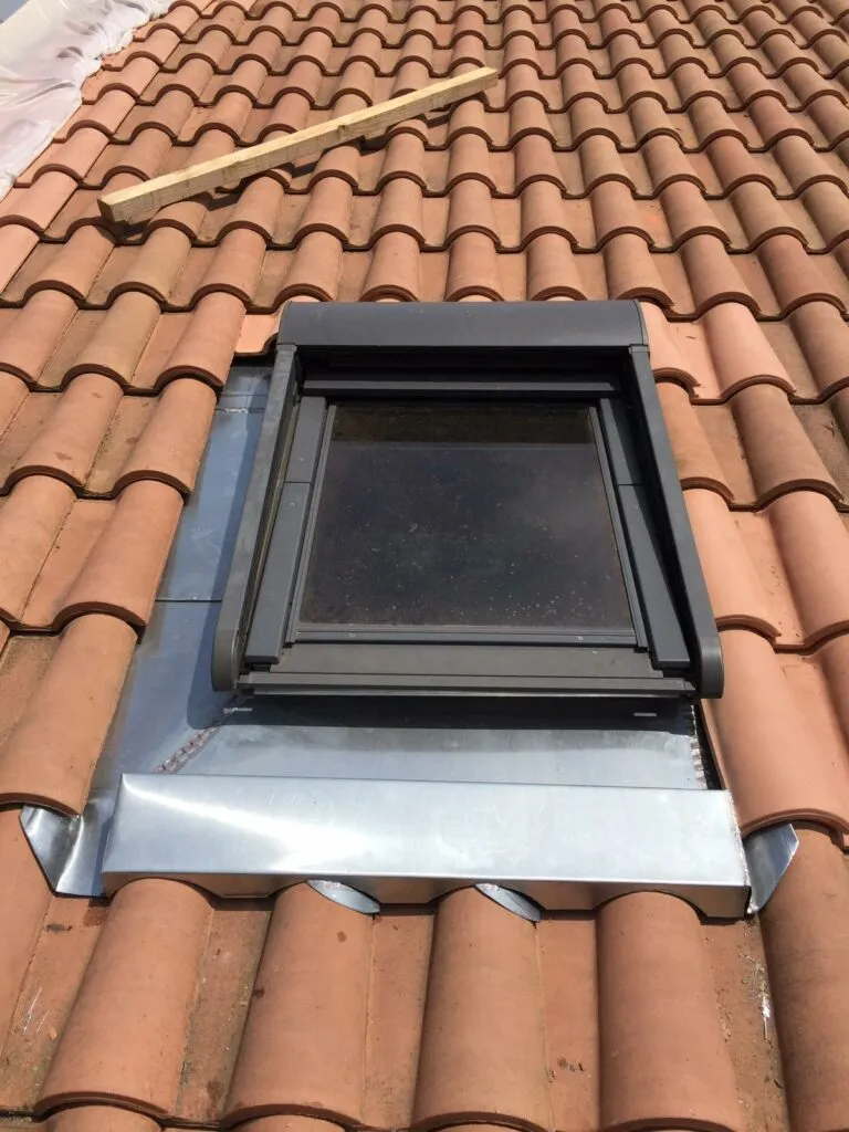 Pose d'une fenêtre de toit avec contour d'étanchéité en zinc façonné sur une couverture en tuiles mécaniques à Toulouse