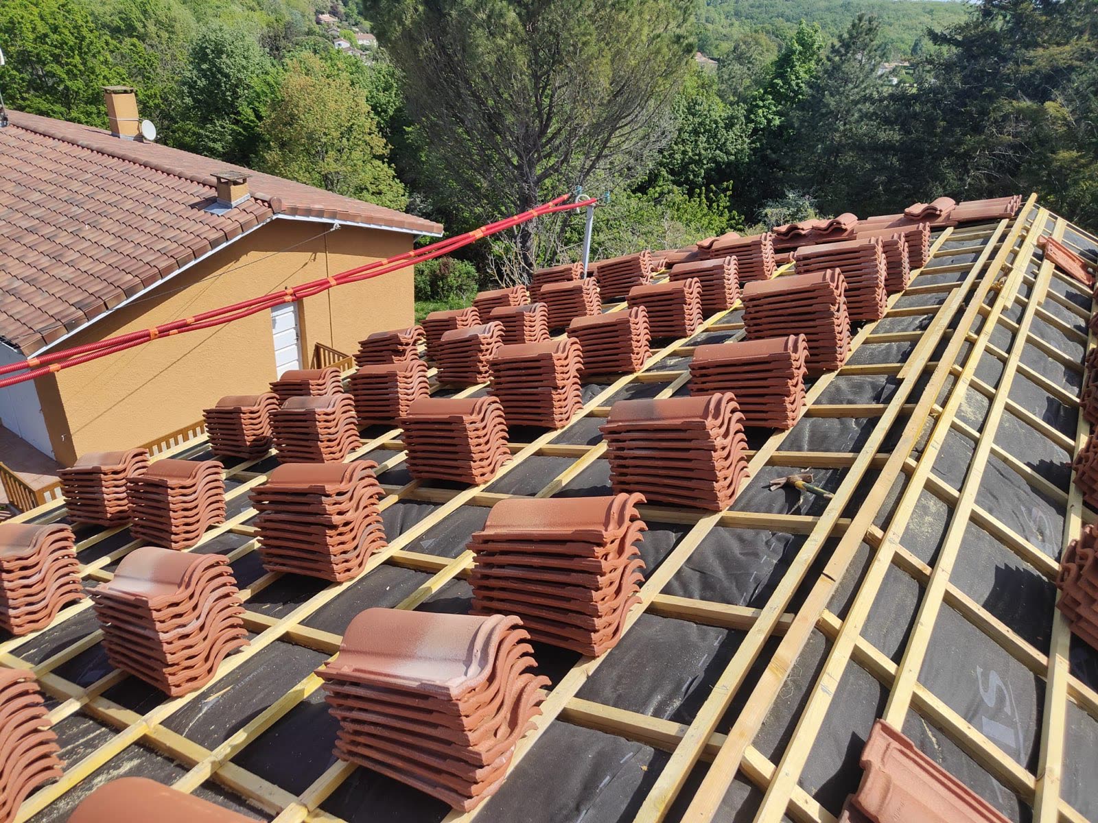 Chantier de réfection de toiture en tuiles, répartition des tuiles sur la charpente avant pose