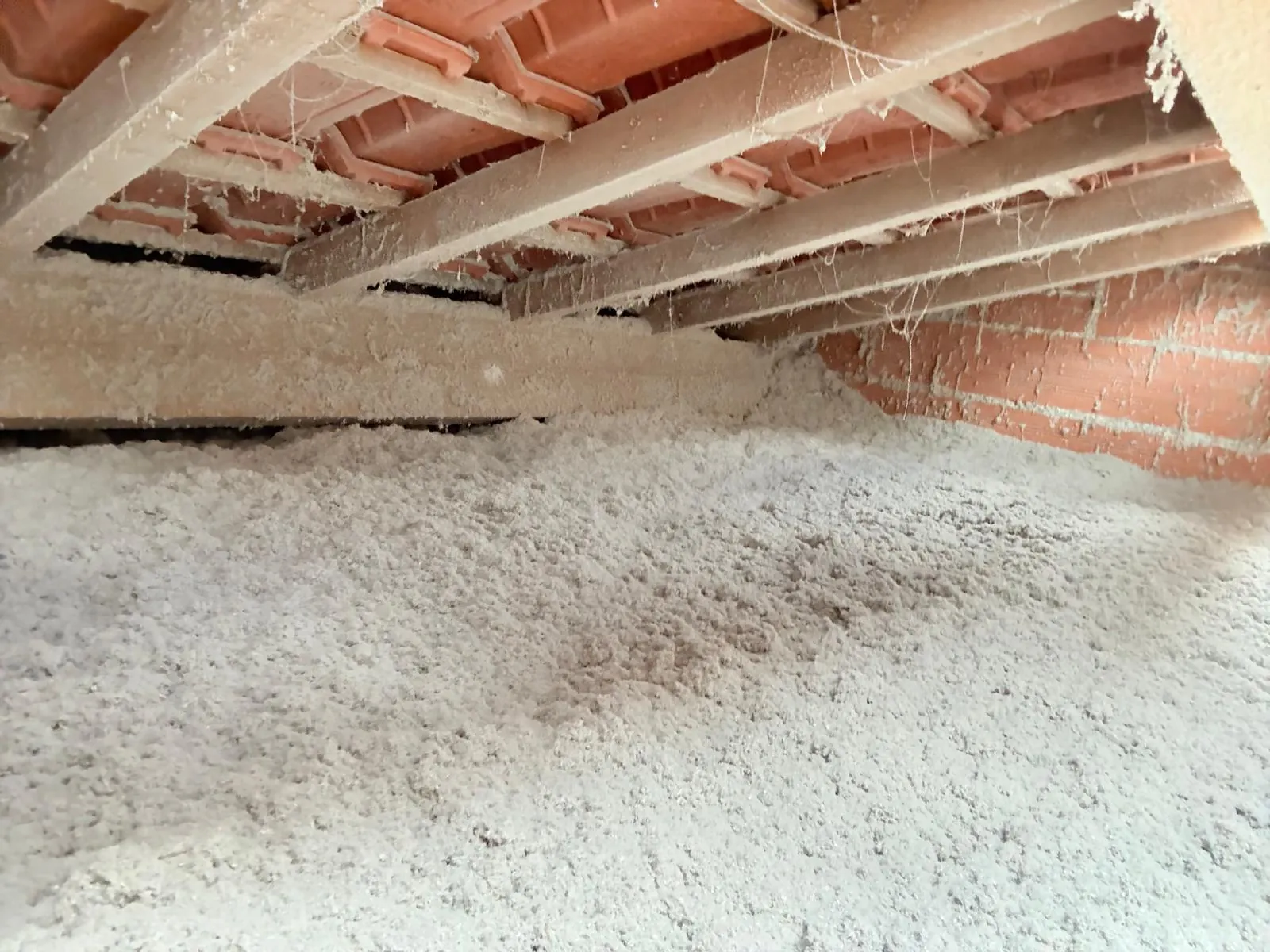 Comble perdu isolé par soufflage d'isolant en flocons sous une sous-toiture en briques et poutres