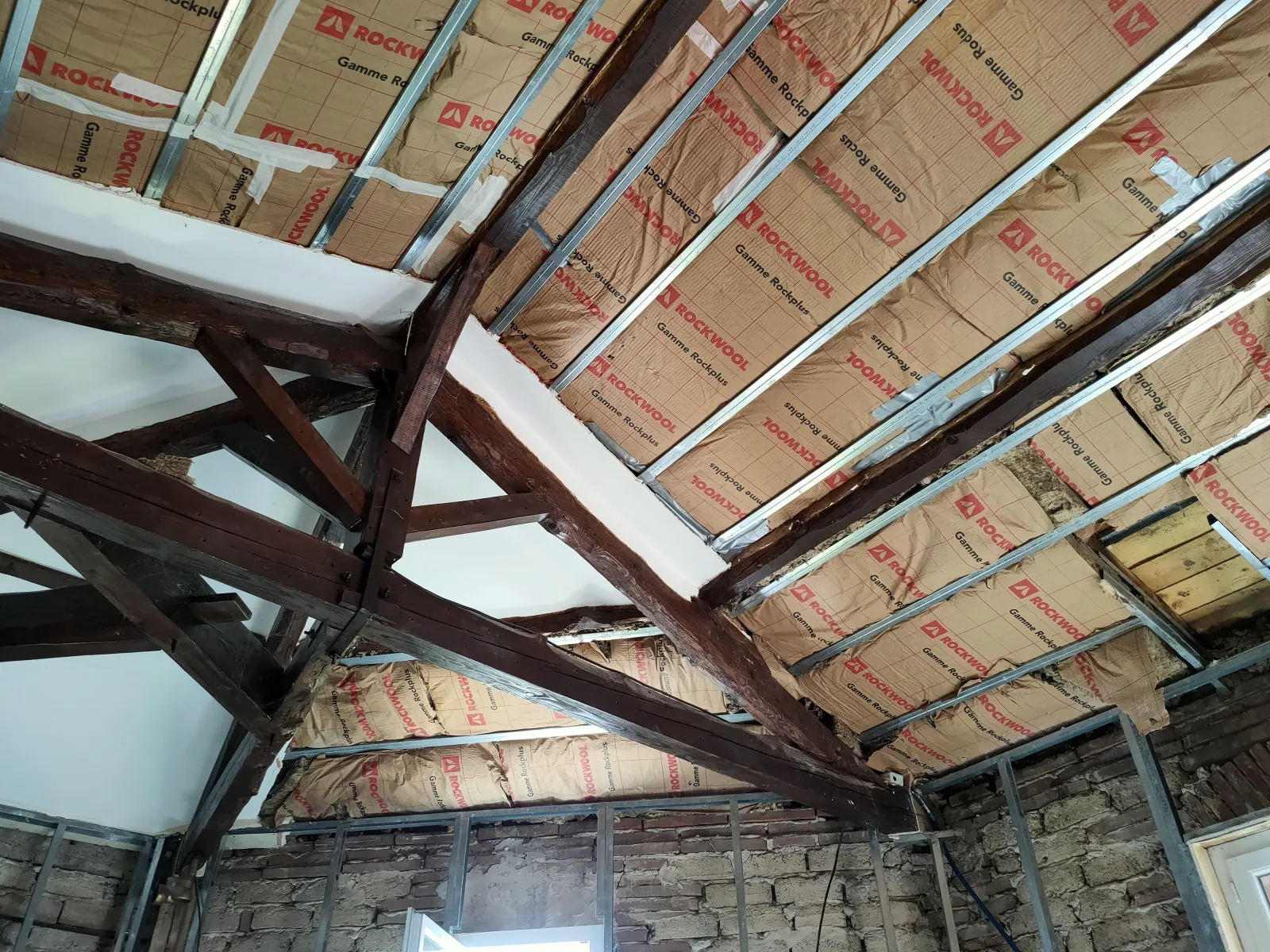 Rampants de toiture isolés avec panneaux de laine de roche entre fermettes métalliques