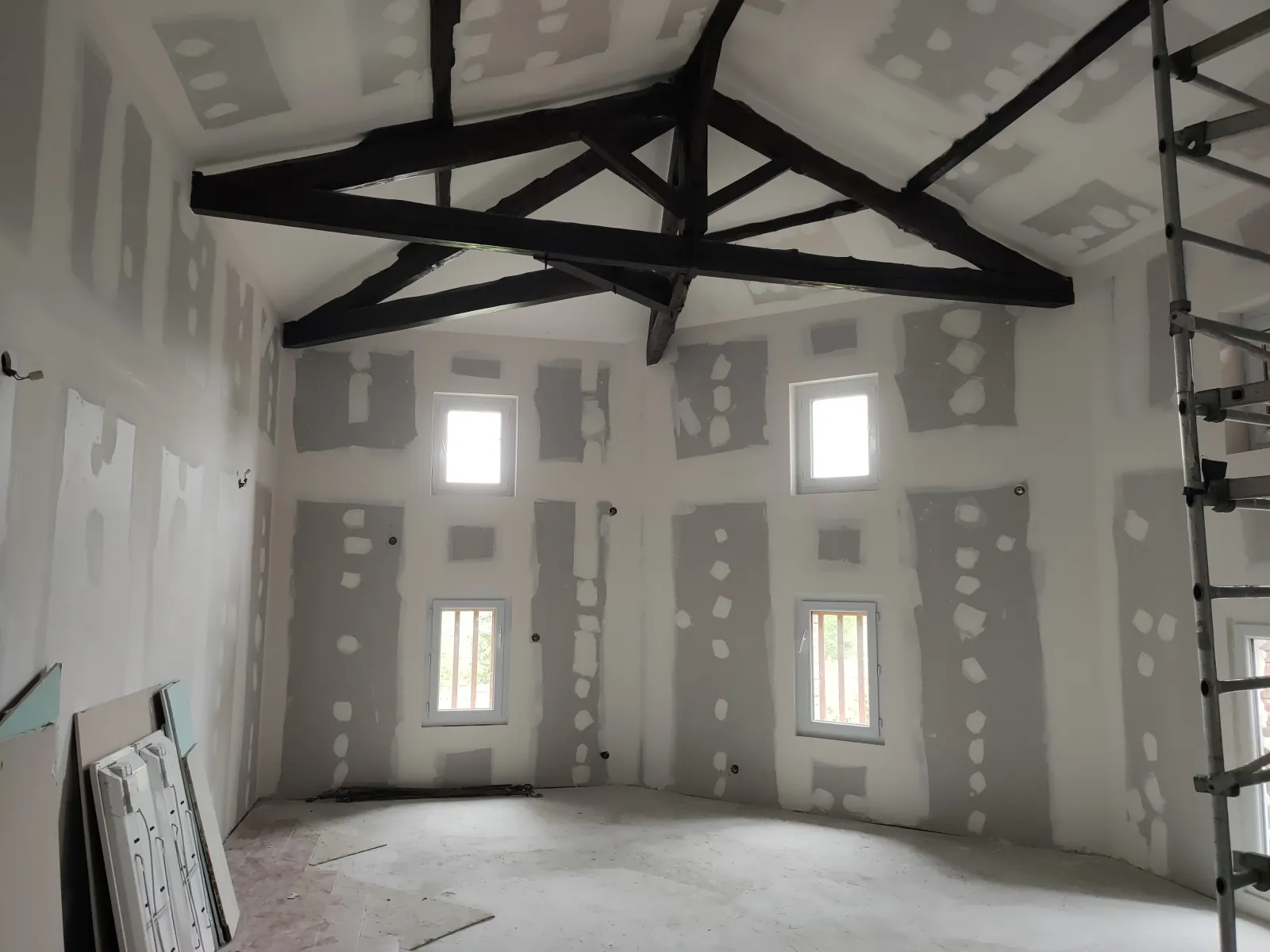 Pièce sous comble rénovée avec ferme de charpente bois apparente et plafond cathédrale en plaques de plâtre
